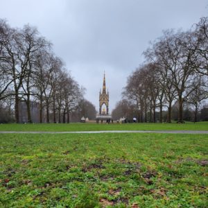 A group of people plays a muddy soccer game under The Albert Memorial.